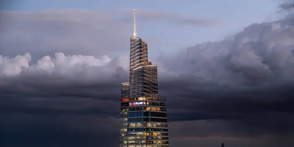 Skyscraper against cloudy sky at dusk.